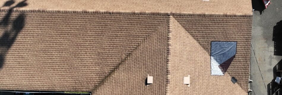 Aerial view of a building with a brown tiled roof and a shadow of a tree cast upon it.