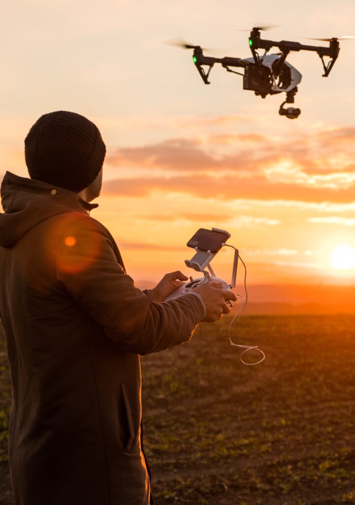 Man operating a drone in a field at sunset.