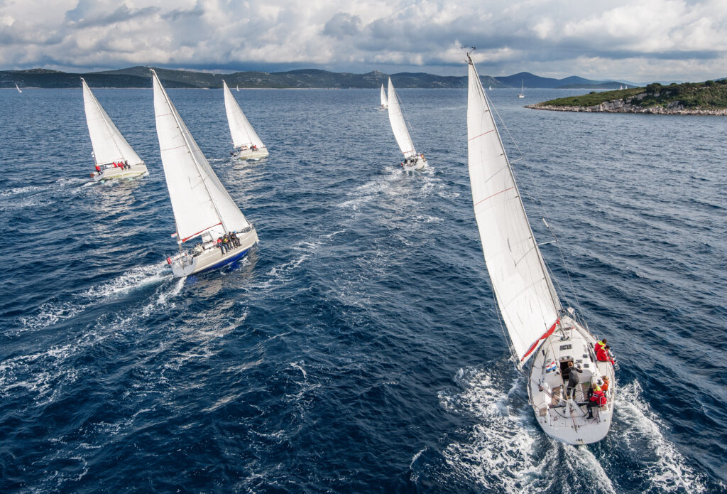 A fleet of sailboats racing in clear blue waters.